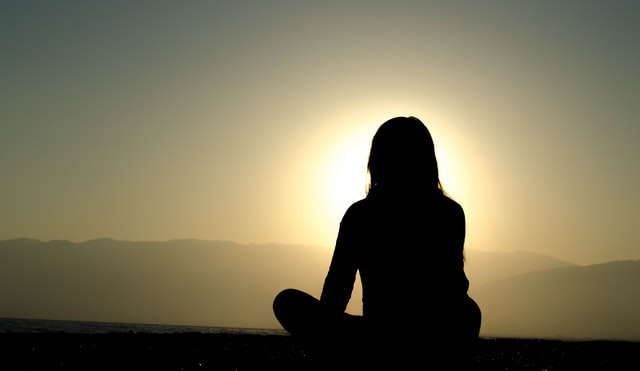 Person sitting in silhouette in sunset